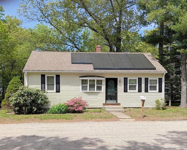 23 Mohawk St, Bellingham, MA 02019 - view of front of home with roof mounted solar panels, a chimney, and roof with shingles