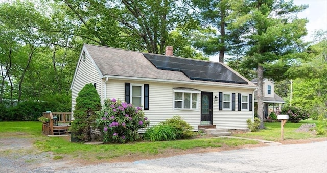 23 Mohawk St, Bellingham, MA 02019 - view of front of house with a chimney, solar panels, a shingled roof, a wooden deck, and a front lawn