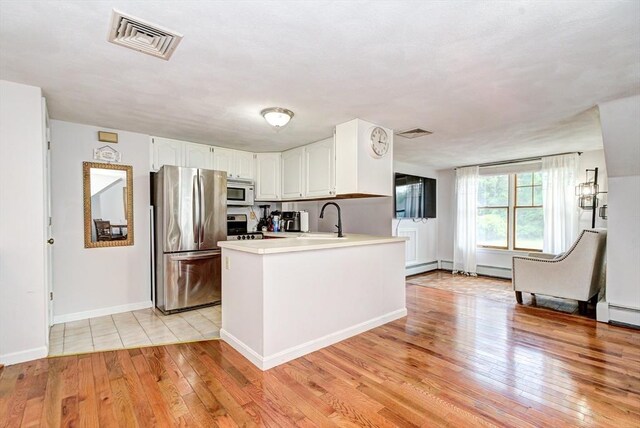11 Balmoral Dr, Methuen, MA 01844 - kitchen featuring appliances with stainless steel finishes, a sink, a baseboard heating unit, white cabinetry, and a peninsula