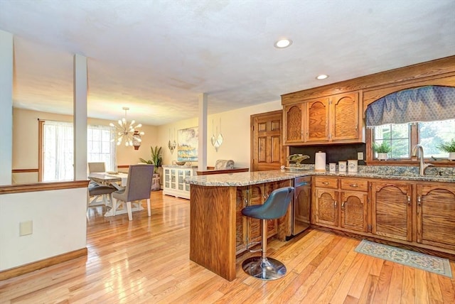 11 Balmoral Dr, Methuen, MA 01844 - kitchen featuring brown cabinetry, a peninsula, light wood-style flooring, a sink, and a chandelier