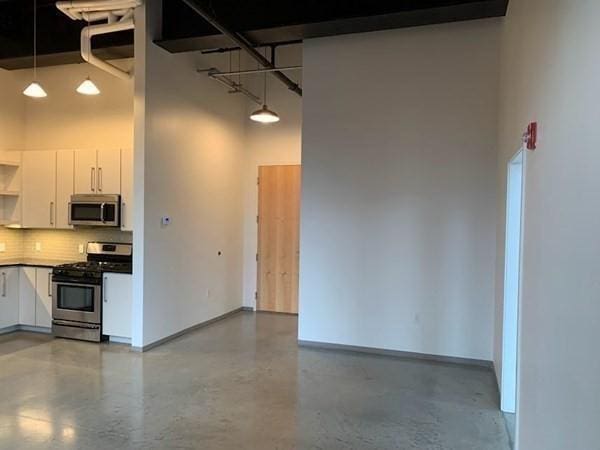 160 Water St Unit 212, Williamstown, MA 01267 - kitchen with stainless steel appliances, white cabinetry, tasteful backsplash, a high ceiling, and concrete floors