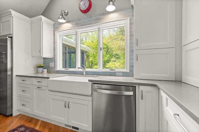 kitchen with stainless steel appliances, light countertops, a sink, and white cabinets