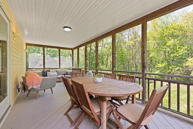 sunroom / solarium with outdoor lounge area, a forest view, and outdoor dining space