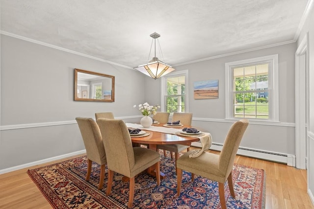dining area featuring crown molding, light wood-style flooring, baseboard heating, and baseboards
