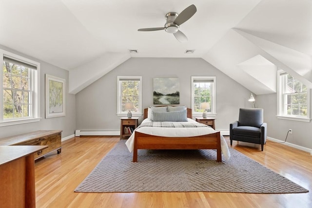 bedroom featuring a baseboard heating unit, multiple windows, vaulted ceiling, and light wood-style flooring