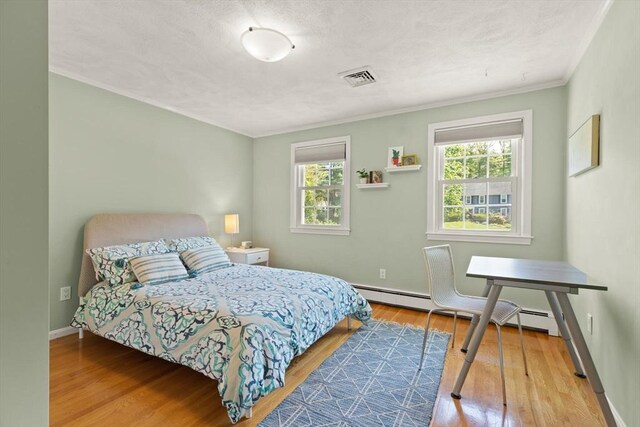 bedroom with wood finished floors, crown molding, baseboards, and baseboard heating
