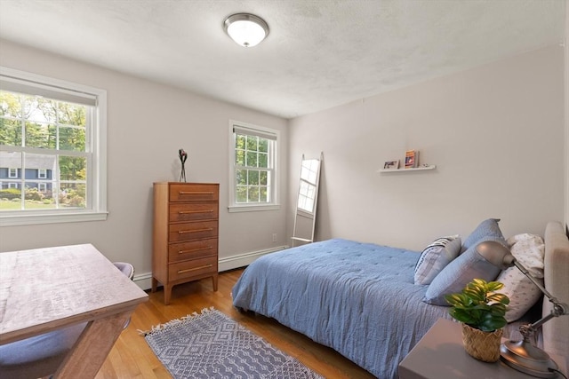 bedroom featuring wood finished floors and a baseboard heating unit