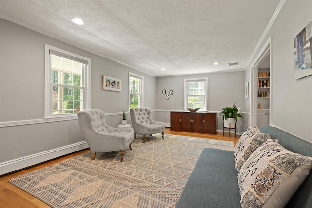 living area featuring ornamental molding, light wood-style floors, recessed lighting, a textured ceiling, and a baseboard heating unit