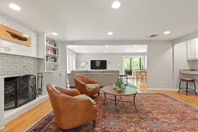living area featuring light wood finished floors, recessed lighting, built in features, a fireplace, and baseboards