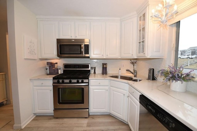 kitchen with appliances with stainless steel finishes, light stone counters, sink, light hardwood / wood-style floors, and white cabinetry