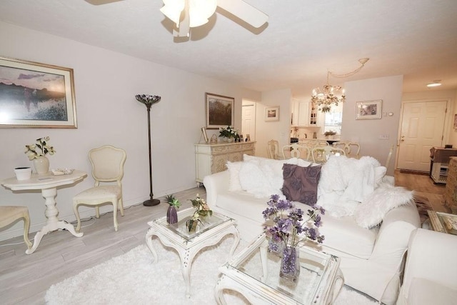 living room featuring light hardwood / wood-style flooring and ceiling fan with notable chandelier