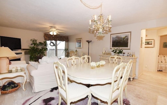 dining space with ceiling fan with notable chandelier and light hardwood / wood-style floors