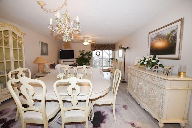 dining area with ceiling fan with notable chandelier and light hardwood / wood-style floors