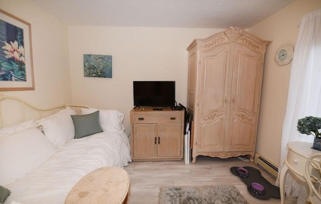 bedroom featuring baseboard heating and light hardwood / wood-style flooring