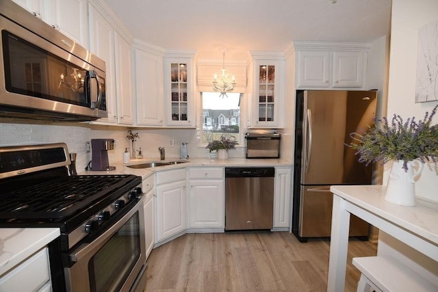 kitchen with white cabinetry, hanging light fixtures, stainless steel appliances, and sink