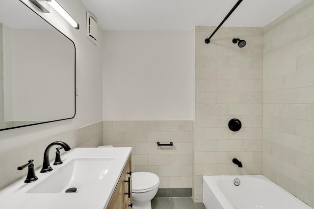 full bathroom featuring a wainscoted wall, tile walls, toilet, vanity, and  shower combination