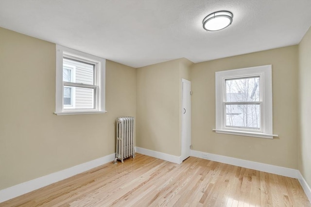 spare room featuring radiator heating unit, wood finished floors, and baseboards