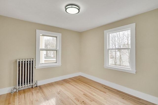 spare room featuring radiator, baseboards, and wood finished floors