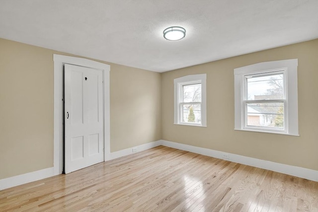 spare room featuring light wood-style flooring and baseboards