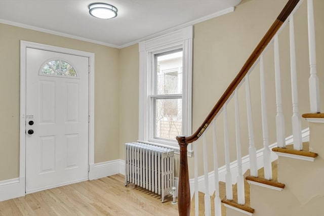 entryway featuring stairs, light wood finished floors, radiator heating unit, and a wealth of natural light