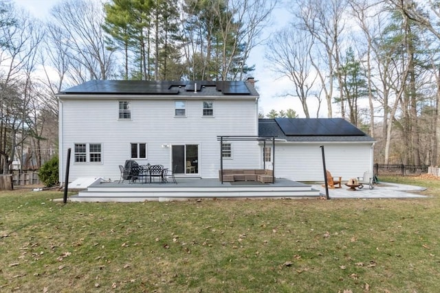 rear view of property featuring an outdoor living space, roof mounted solar panels, fence, a yard, and a wooden deck