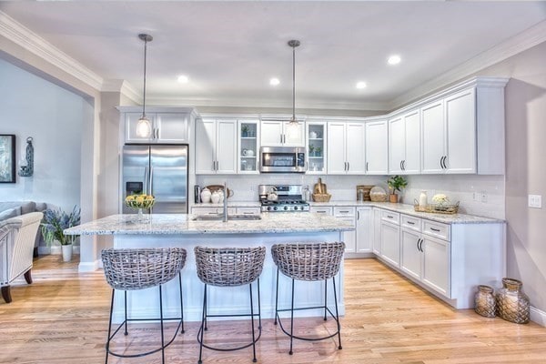 kitchen with pendant lighting, sink, stainless steel appliances, and an island with sink