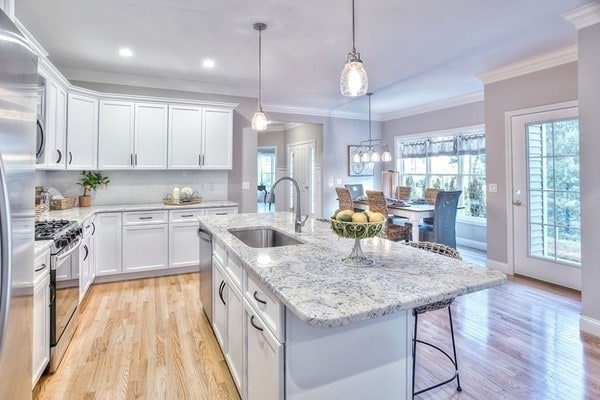 kitchen featuring appliances with stainless steel finishes, sink, a center island with sink, light hardwood / wood-style flooring, and white cabinets