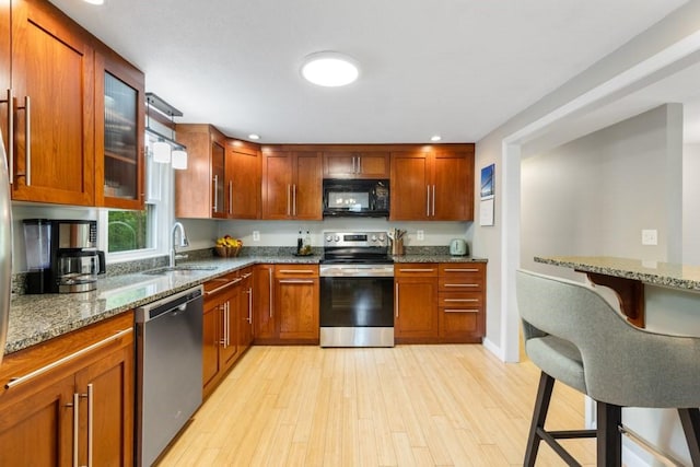 13 Shagbark Rd, Sandwich, MA 02644 - kitchen with appliances with stainless steel finishes, a sink, light stone countertops, light wood finished floors, and glass insert cabinets