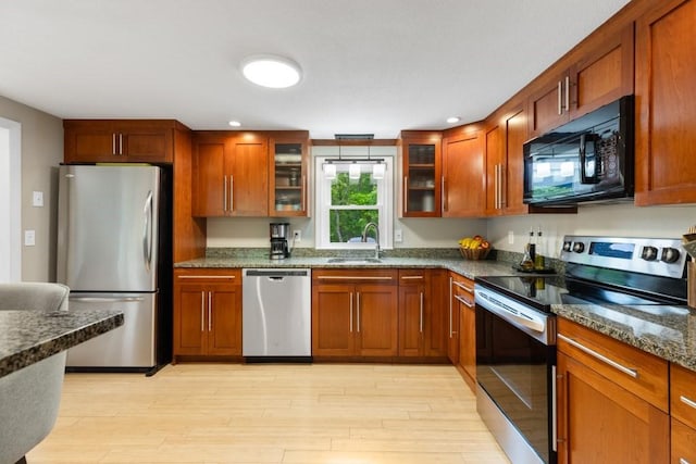 13 Shagbark Rd, Sandwich, MA 02644 - kitchen with appliances with stainless steel finishes, a sink, light wood-style floors, dark stone countertops, and glass insert cabinets