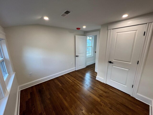 unfurnished bedroom with dark hardwood / wood-style flooring and vaulted ceiling