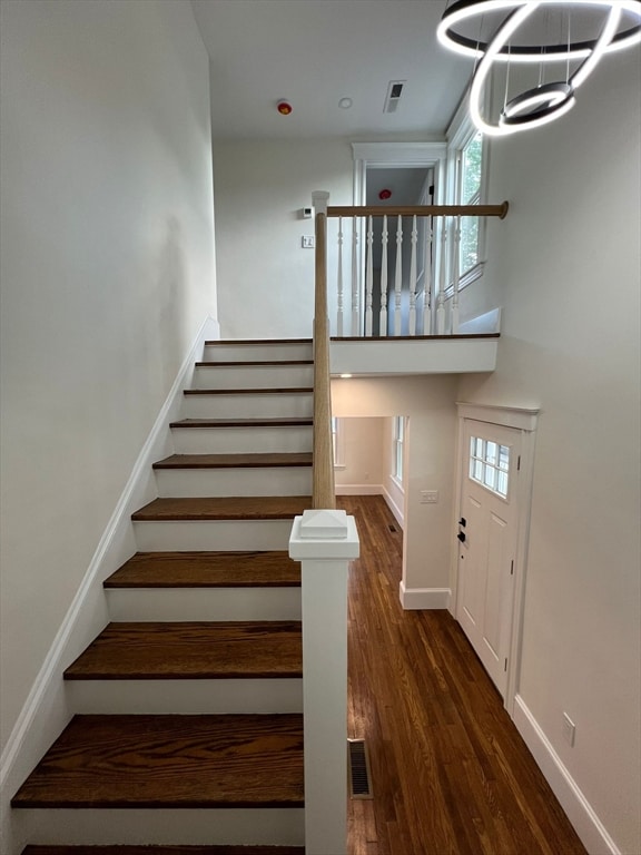 stairs with a chandelier and dark hardwood / wood-style flooring