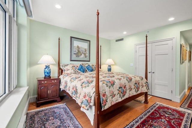 bedroom featuring baseboard heating, light wood-type flooring, and a closet