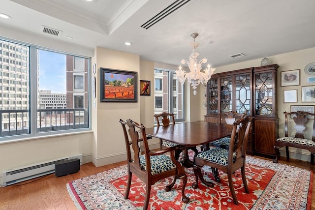 dining space featuring a baseboard radiator, ornamental molding, a notable chandelier, hardwood / wood-style flooring, and a tray ceiling