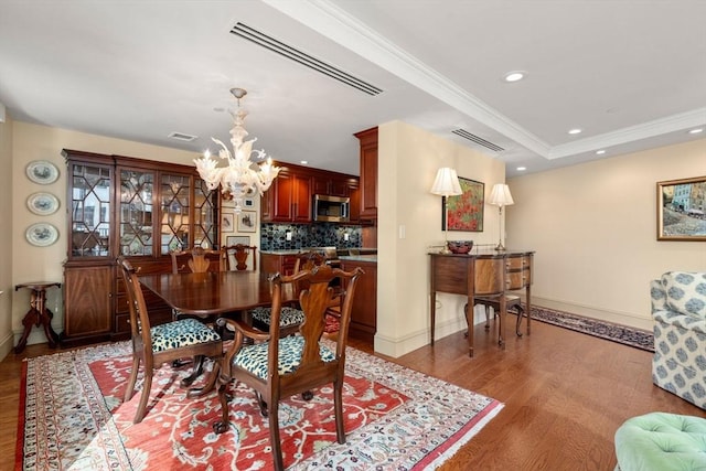 dining room featuring crown molding, hardwood / wood-style floors, a chandelier, and a tray ceiling