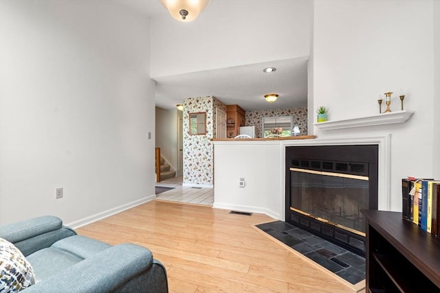 42 Brickett Hill Cir Unit 114, Haverhill, MA 01830 - living area featuring stairs, a fireplace with flush hearth, wood finished floors, and a towering ceiling