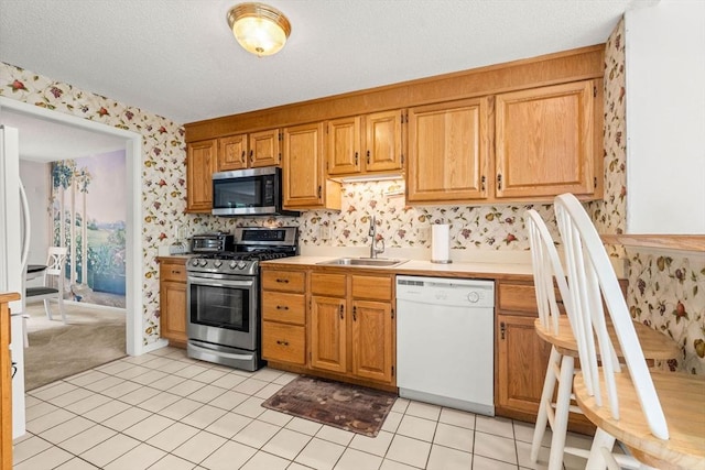 42 Brickett Hill Cir Unit 114, Haverhill, MA 01830 - kitchen featuring stainless steel appliances, wallpapered walls, light countertops, light tile patterned floors, and a textured ceiling