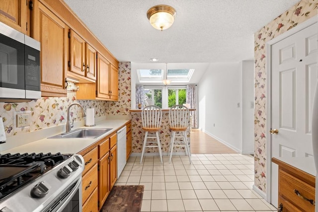 42 Brickett Hill Cir Unit 114, Haverhill, MA 01830 - kitchen with stainless steel appliances, a skylight, wallpapered walls, light countertops, and a textured ceiling