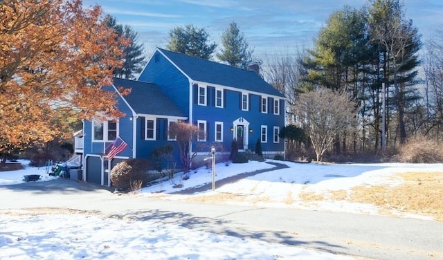 colonial inspired home with a chimney and a garage