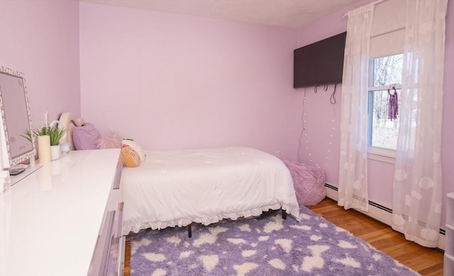 bedroom featuring a baseboard heating unit and light wood finished floors