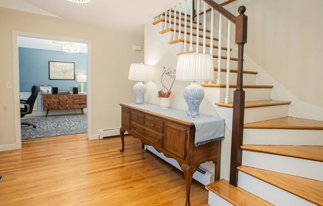 stairway with a baseboard radiator, baseboards, and wood finished floors