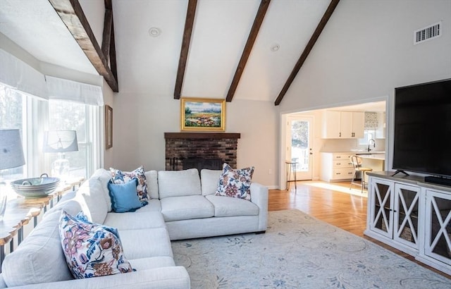 living room featuring light wood finished floors, plenty of natural light, a fireplace, and visible vents