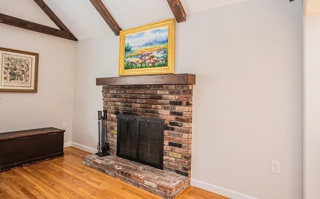 living room with a fireplace, vaulted ceiling with beams, wood finished floors, and baseboards