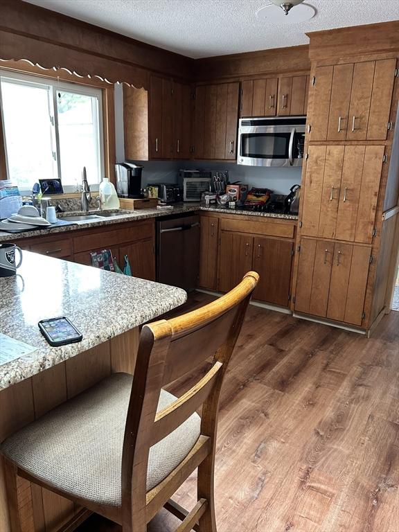 554 Main St, Becket, MA 01223 - kitchen featuring stainless steel microwave, dishwasher, wood finished floors, a sink, and a textured ceiling