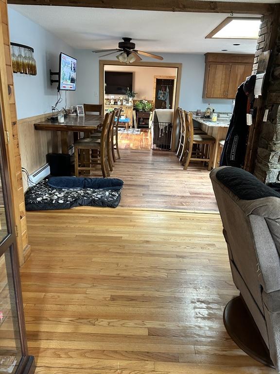 554 Main St, Becket, MA 01223 - living room with a ceiling fan, a baseboard heating unit, light wood-type flooring, and wainscoting