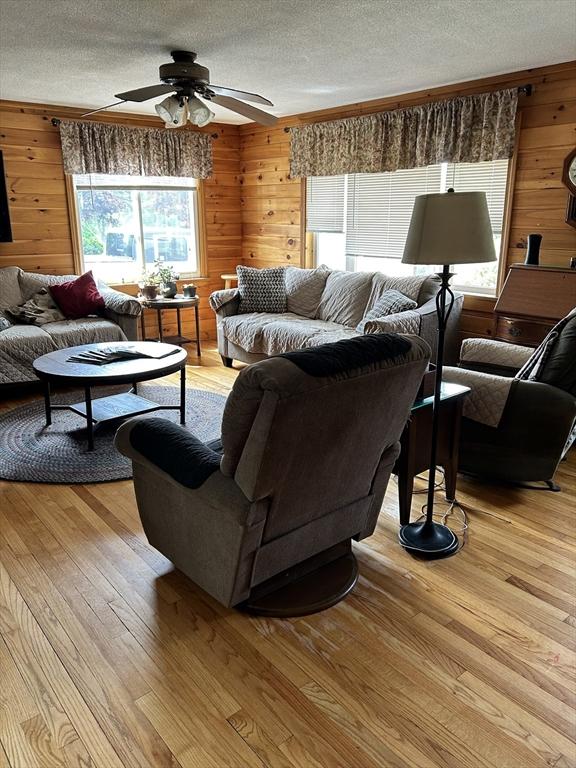 554 Main St, Becket, MA 01223 - living area featuring wooden walls, a textured ceiling, a ceiling fan, and light wood-style floors