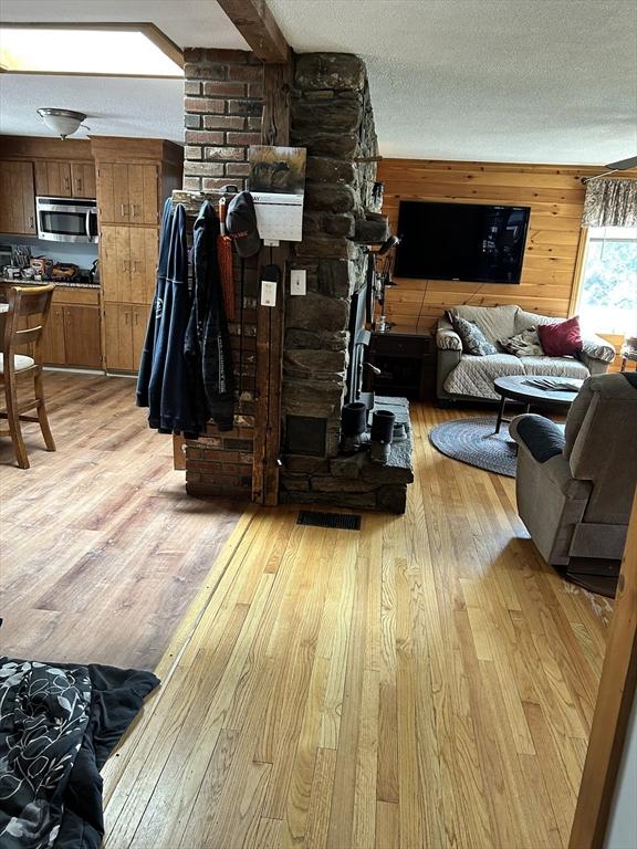 554 Main St, Becket, MA 01223 - living area featuring light wood-type flooring, a textured ceiling, and wood walls