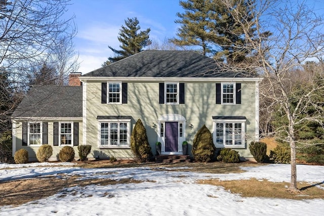 colonial house with a chimney and roof with shingles