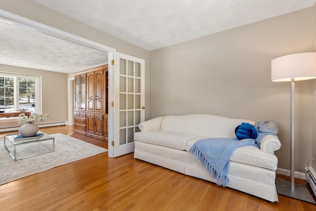 sitting room featuring a baseboard radiator, baseboards, and wood finished floors