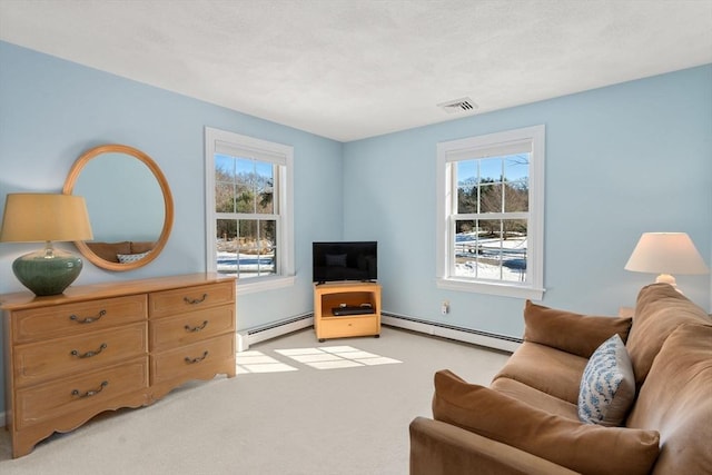 sitting room with a baseboard heating unit, visible vents, and plenty of natural light