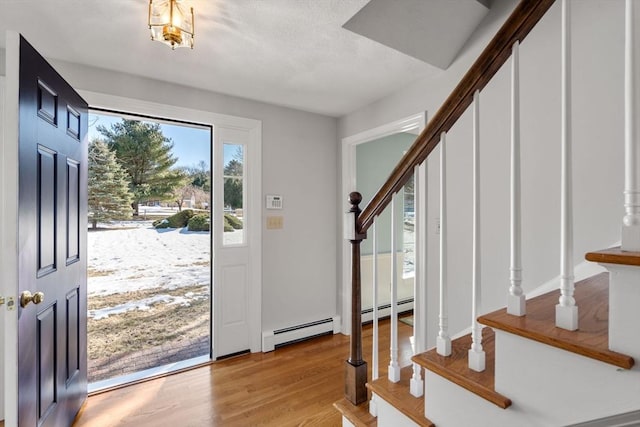 entrance foyer featuring a baseboard radiator, stairs, and light wood-style flooring